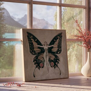 May include: A framed print of a butterfly with a woman's body in the center. The butterfly has black and yellow wings with red accents. The print is on a light brown background and is framed in a light wood frame.