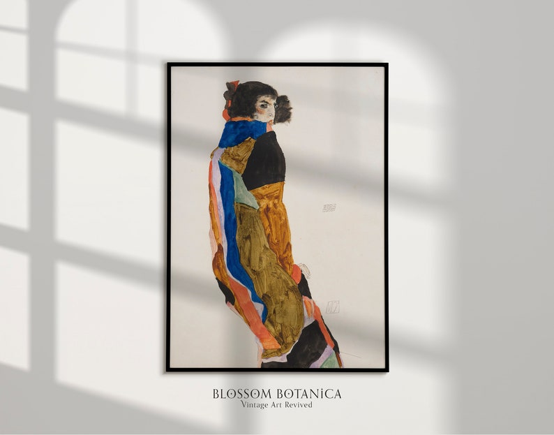 May include: A vintage art print of a woman in a colorful, geometric patterned dress. The woman is standing with her back to the viewer, looking over her shoulder. The print is in a black frame.