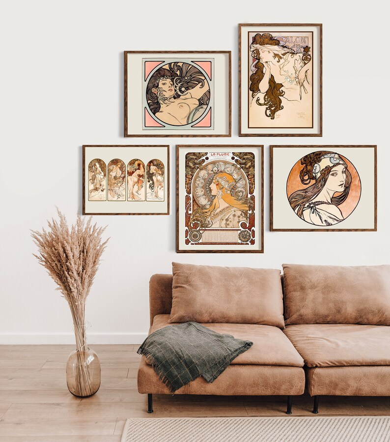 May include: Five framed art prints featuring illustrations of women in Art Nouveau style. The prints are arranged on a white wall above a brown leather couch.