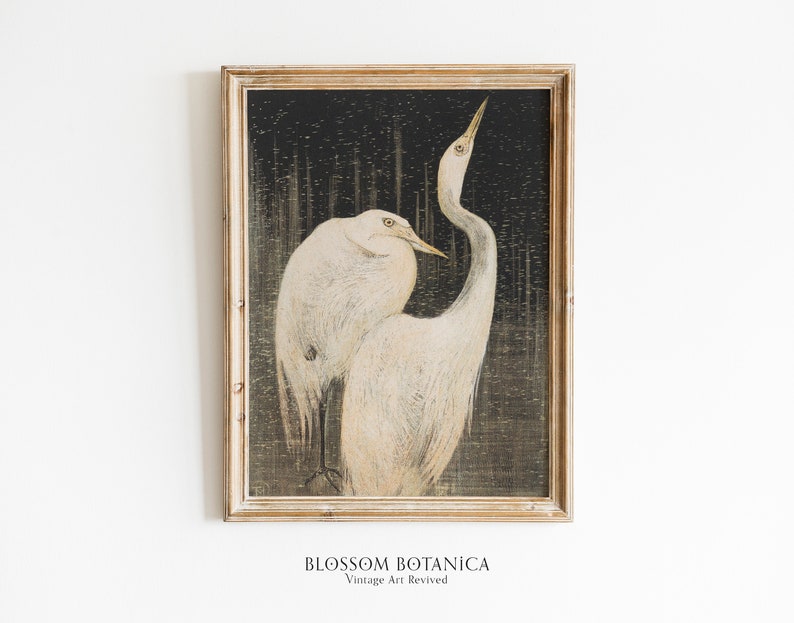 May include: A vintage framed print of two white birds with long necks and beaks, standing on a dark background with a textured pattern. The print is in a light wood frame.