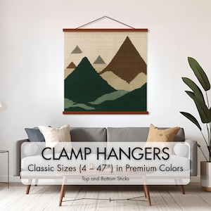 May include: A wall hanging with a mountain landscape design in shades of green, brown, and beige. The artwork is displayed with a wooden clamp hanger. The text "CLAMP HANGERS" and "Classic Sizes (4 - 47") in Premium Colors" is visible.