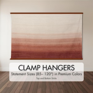 May include: A large, rectangular wall hanging with a gradient color scheme, transitioning from off-white at the top to deep red at the bottom. The fabric is held by wooden clamp hangers. Text on the image reads "CLAMP HANGERS" and "Statement Sizes (85-120") in Premium Colors".