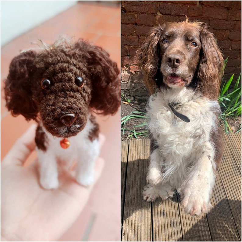 May include: A brown and white crocheted dog toy with a bell on its collar, next to a real brown and white Springer Spaniel dog sitting on a wooden deck.