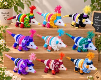 May include: A collection of nine crocheted opossum figurines arranged on a wooden tiered display. Each opossum features a striped body, a pointed snout, a small pom-pom on its head, and a ruffled collar in various bright, multi-colored yarn patterns.