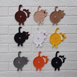 Può includere: Nove sottobicchieri fatti a mano all'uncinetto a forma di sedere di gatto in vari colori, tra cui marrone, nero, bianco, giallo, grigio e arancione. Ogni sottobicchiere presenta un design circolare con il posteriore e la coda di un gatto, con dettagli rosa e verdi.