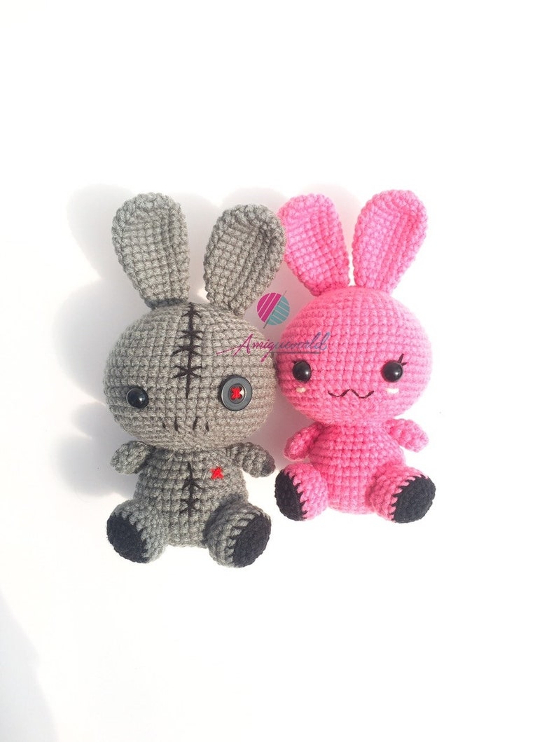 May include: Two crocheted bunny plushies, one grey with a button eye and stitched details, the other pink with embroidered eyes and a sweet expression.