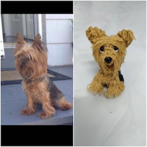Puede incluir: Un perro Yorkshire Terrier marr&oacute;n y negro sentado en una superficie gris. Junto al perro hay un perro de peluche de ganchillo con pelo marr&oacute;n, ojos negros y nariz negra.