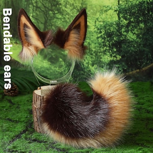 Puede incluir: Un conjunto de orejas y cola de zorro, con pelo sintético marrón, beige y blanco. Las orejas están unidas a una diadema transparente y la cola es esponjosa. El texto "Bendable ears" es visible.