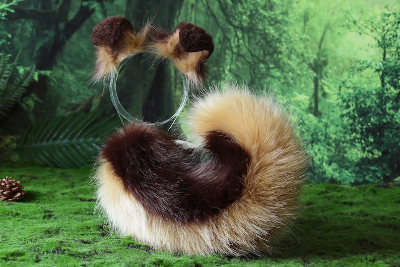 Pode incluir: Um conjunto de cauda e faixa de cabelo em pele sint&eacute;tica castanha, bege e branca. A cauda &eacute; encaracolada e fofa, e a faixa de cabelo apresenta pequenas orelhas arredondadas. O conjunto foi concebido para se assemelhar a um animal.