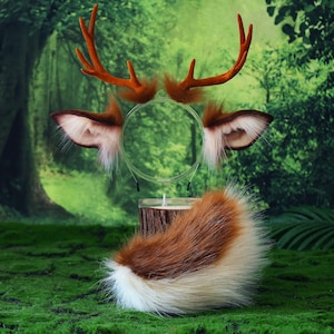 Peut inclure: Ensemble de costume sur le thème de la forêt, comprenant des oreilles, des bois et une queue de cerf en fausse fourrure marron. Les oreilles et la queue ont des accents blancs. Les bois sont brun-rouge. L'ensemble est présenté sur une surface verte et mousseuse.