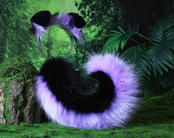 Pode incluir: Um conjunto de fantasia de pele com uma tiara com orelhas pretas e roxas e uma cauda combinando. A cauda é preta e roxa, com um design enrolado. Para cosplay ou fantasias.