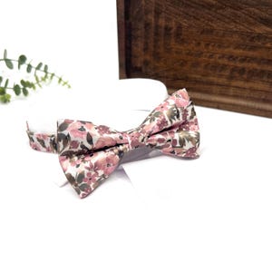 Peut inclure: Un nœud papillon floral rose et vert. Le nœud papillon est fait d'un tissu doux et soyeux et a une forme classique de nœud papillon.