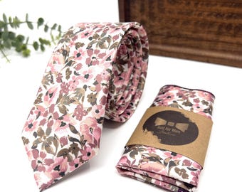 May include: A pink and brown floral patterned tie and pocket square set. The tie is rolled up and the pocket square is folded. The pocket square has a brown tag with the text "Just for Men" and a bowtie icon.