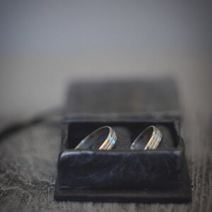 May include: Two silver wedding bands in a black velvet ring box.