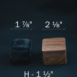 May include: Two ring boxes, one black velvet and one wooden, with measurements labelled in inches. The black box is 1 7/8 inches wide and the wooden box is 2 1/8 inches wide. The height of both boxes is 1 1/2 inches.