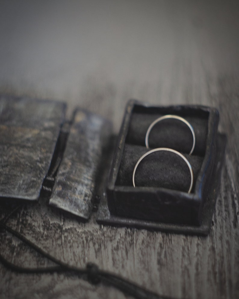 May include: Two silver rings in a black leather ring box with a black velvet interior.