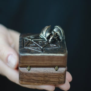 May include: A small wooden box with a carved dragon design on the lid. The box is closed and has brass hinges.