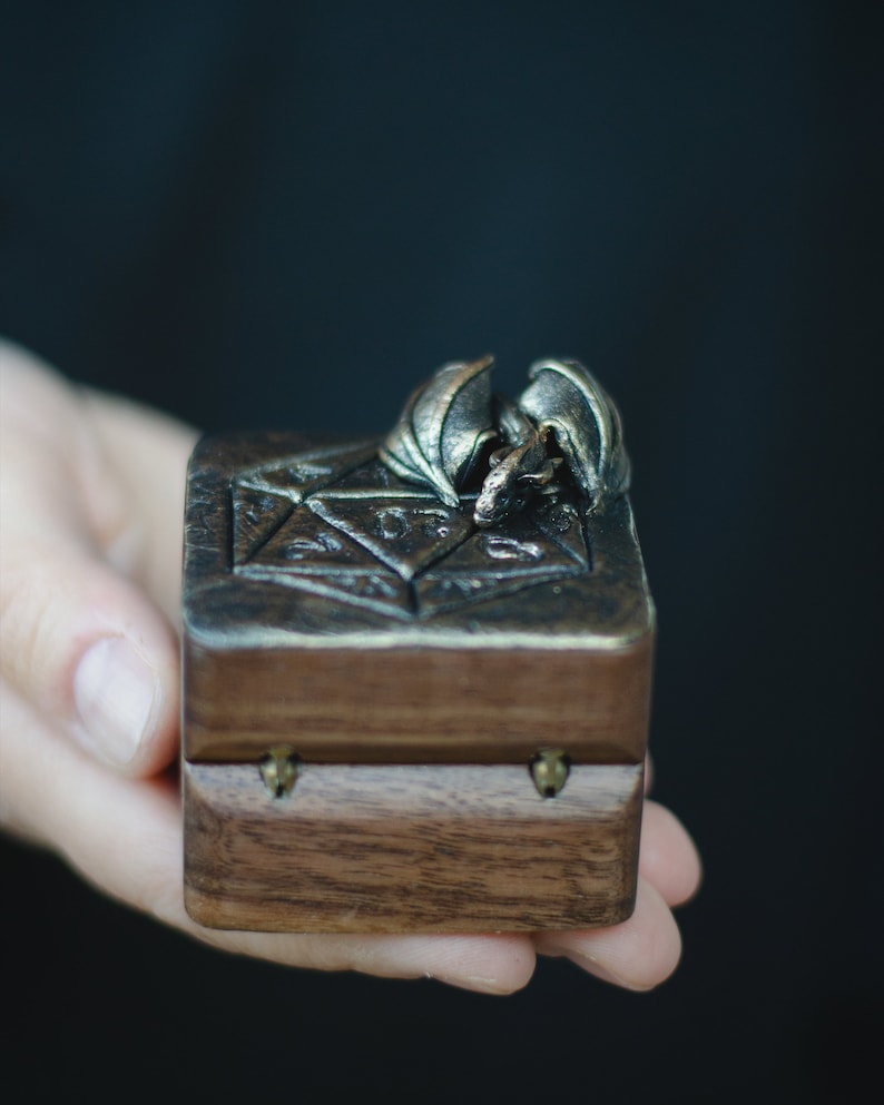 May include: A small wooden box with a carved dragon design on the lid. The box is closed and has brass hinges.