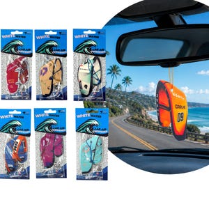 Puede incluir: Ambientadores para coche con forma de tablas de surf y cometas. El embalaje muestra el texto "WHITE WATER CAR AIR FRESHENER". Un ambientador naranja y amarillo cuelga del espejo retrovisor, con "NORTH CARVE 09".