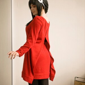 May include: A woman wearing a red dress with a back slit and a white headband. The dress has a loose fit and is made of a soft, comfortable fabric.