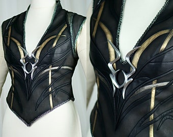 May include: A black leather vest with gold and silver accents. The vest has a pointed collar and a decorative silver piece in the center.