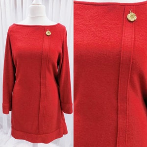 May include: A red long-sleeved dress with a boat neck and gold button detail. The dress has a fitted bodice and a slightly flared skirt.