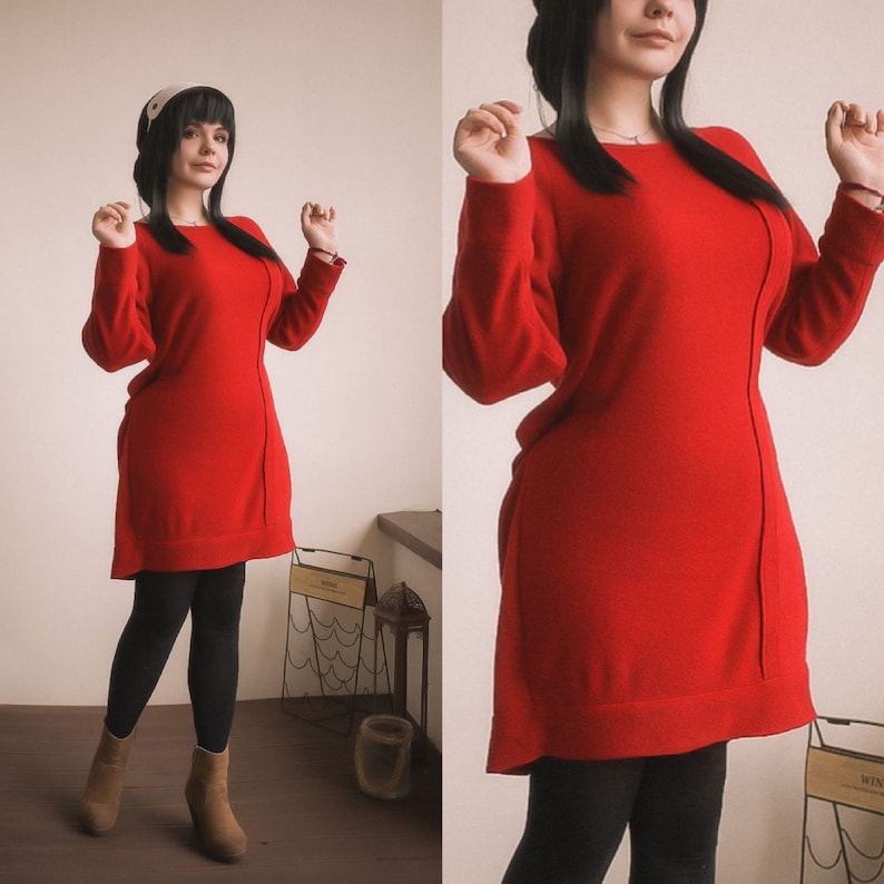 May include: A woman wearing a red sweater dress with black leggings and brown boots. She is standing in front of a white wall.