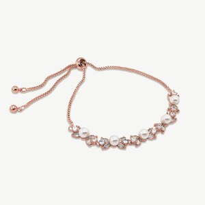 May include: Rose gold bracelet with a delicate design. The bracelet features faux pearls and clear crystals. The adjustable chain allows for a custom fit. A beautiful piece of jewellery, perfect for special occasions.