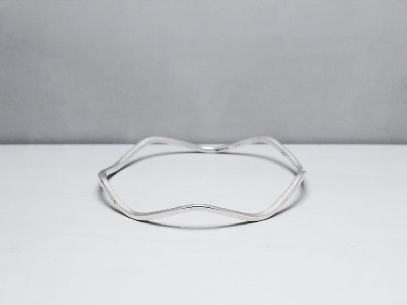 May include: A silver wavy bangle bracelet.