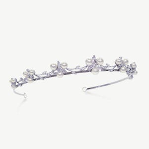 May include: A silver-toned tiara with a delicate floral design. The tiara features faux pearls and clear crystals, with a curved band for comfortable wear. The design includes small leaves and pearl accents, creating an elegant and refined look.
