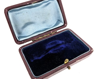 May include: An empty, burgundy velvet-lined jewelry box with a hinged lid and a gold-colored clasp.