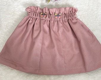High-waisted pink cotton skirt with decorative buttons