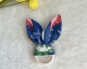 Teething ring - Rabbit ears rattle - Dinosaurs on blue background