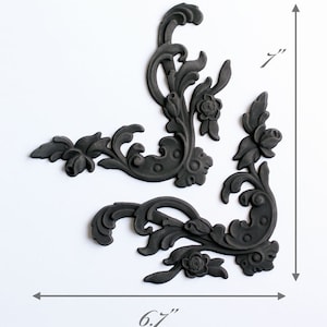 May include: Intricate Grace, a set of three black decorative corner moldings with a floral design. The moldings are 6.7 inches wide and 7 inches tall.