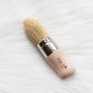 May include: A small, round, wooden-handled paint brush with natural bristles. The brush is labeled "Dixie Belle Paint Company".