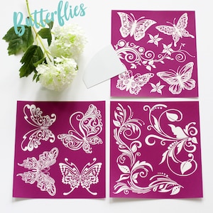 May include: Four reusable stencils with intricate butterfly and floral designs. The stencils are white on a magenta background. The stencils are perfect for crafting, painting, and decorating.