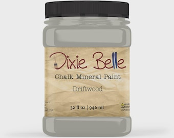 May include: A plastic jar of Dixie Belle Chalk Mineral Paint in the colour Driftwood. The label features a tan, textured background with the brand name, product type, and the volume of 946 ml. The jar has a black screw-top lid and contains grey paint.