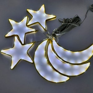 May include: A set of three gold-colored wire star and crescent moon shapes with white LED lights. The lights are strung together with a clear wire.
