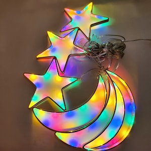 May include: A set of three string lights shaped like stars and a crescent moon. The lights are multi-colored and glow with a warm white light.