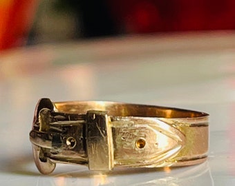 May include: A gold-toned ring with a buckle design. The ring is made of metal and has a polished finish.