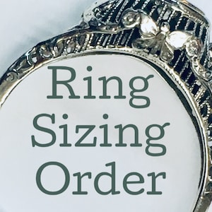 May include: A close-up of a silver ring with intricate detailing. The ring has a butterfly design and the words "Ring Sizing Order" are printed on the background.