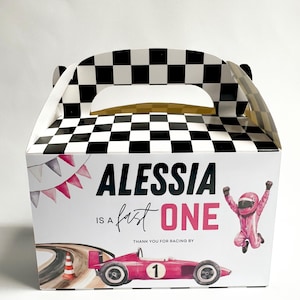 May include: A white party favor box with a black and white checkered pattern on the top and handle. The front features the text "Alessia is a fast one" with a pink race car and a cartoon racer.