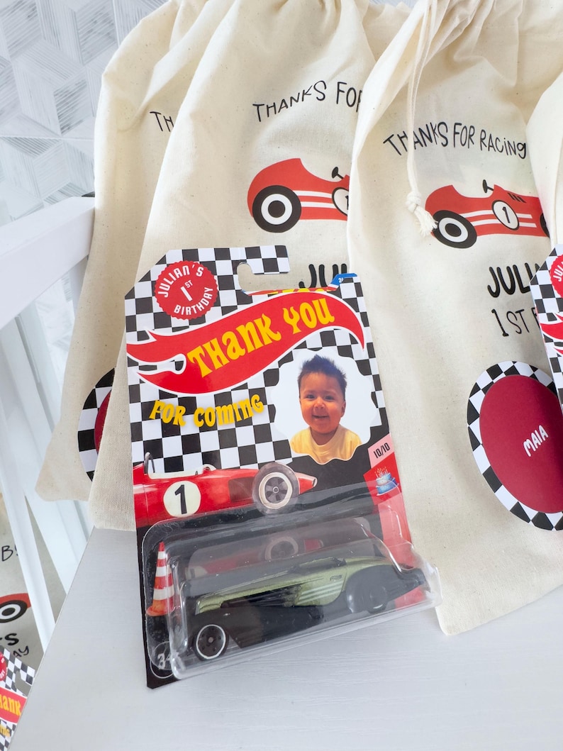 May include: A collection of party favors for a child's birthday. The favors include small drawstring bags with a red race car graphic and the text "THANKS FOR RACING". A toy race car is in a plastic package with the text "THANK YOU".