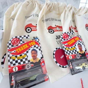 May include: Cream-colored drawstring bags with a red race car graphic and the text "THANKS FOR RACING".  Also, toy race cars in packaging with a child's photo and the words "THANK YOU FOR COMING".