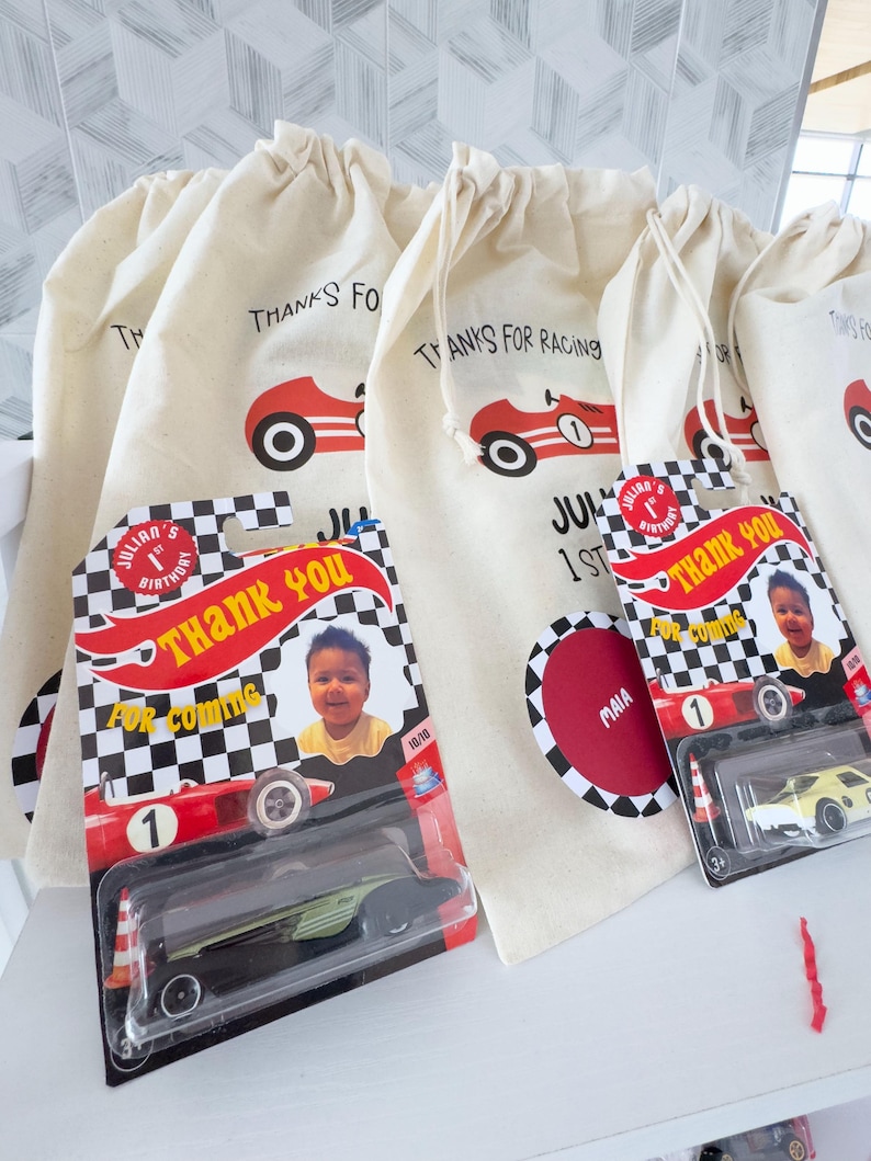 May include: Cream-colored drawstring bags with a red race car graphic and the text "THANKS FOR RACING".  Also, toy race cars in packaging with a child's photo and the words "THANK YOU FOR COMING".