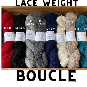 May include: Lace weight yarn in ten colors: red, black, light gray, dark gray, navy, white, taupe, turquoise. The yarn is a bouclé style, with a fuzzy texture. The yarn is labeled "Carnival" and is made by The Alpaca Yarn Company.