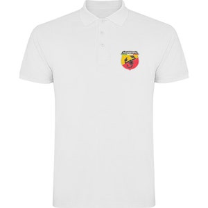 May include: White polo shirt with a small embroidered logo of a scorpion in a shield with the word "ABARTH" above it.