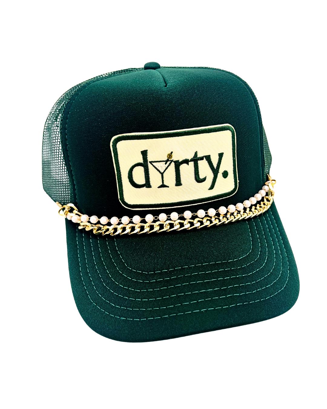 May include: Dark green trucker hat with a white and gold chain and pearl embellishment. The hat features a rectangular patch with the word "dirty" and a martini glass design. The hat has a mesh back.