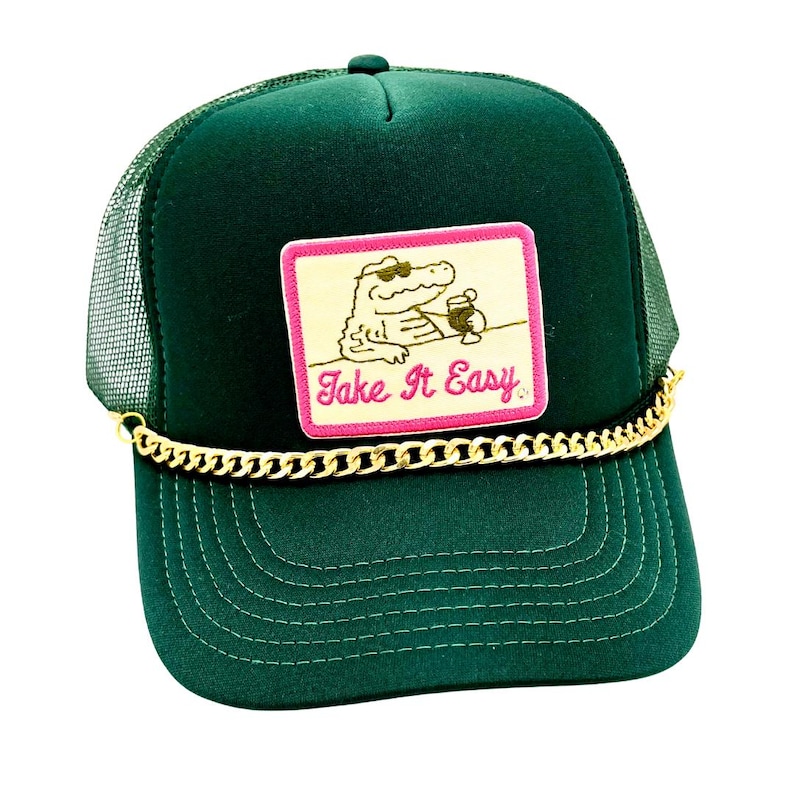 Pode incluir: Bon&eacute; de caminhoneiro verde escuro com parte traseira em rede e aba curva. A frente apresenta um patch com um jacar&eacute; usando &oacute;culos de sol e segurando uma bebida, com o texto "Take It Easy". Uma corrente dourada adorna a aba.