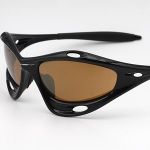 May include: Black wraparound sunglasses with brown lenses. The sunglasses have a sporty design with a curved frame and multiple vents.